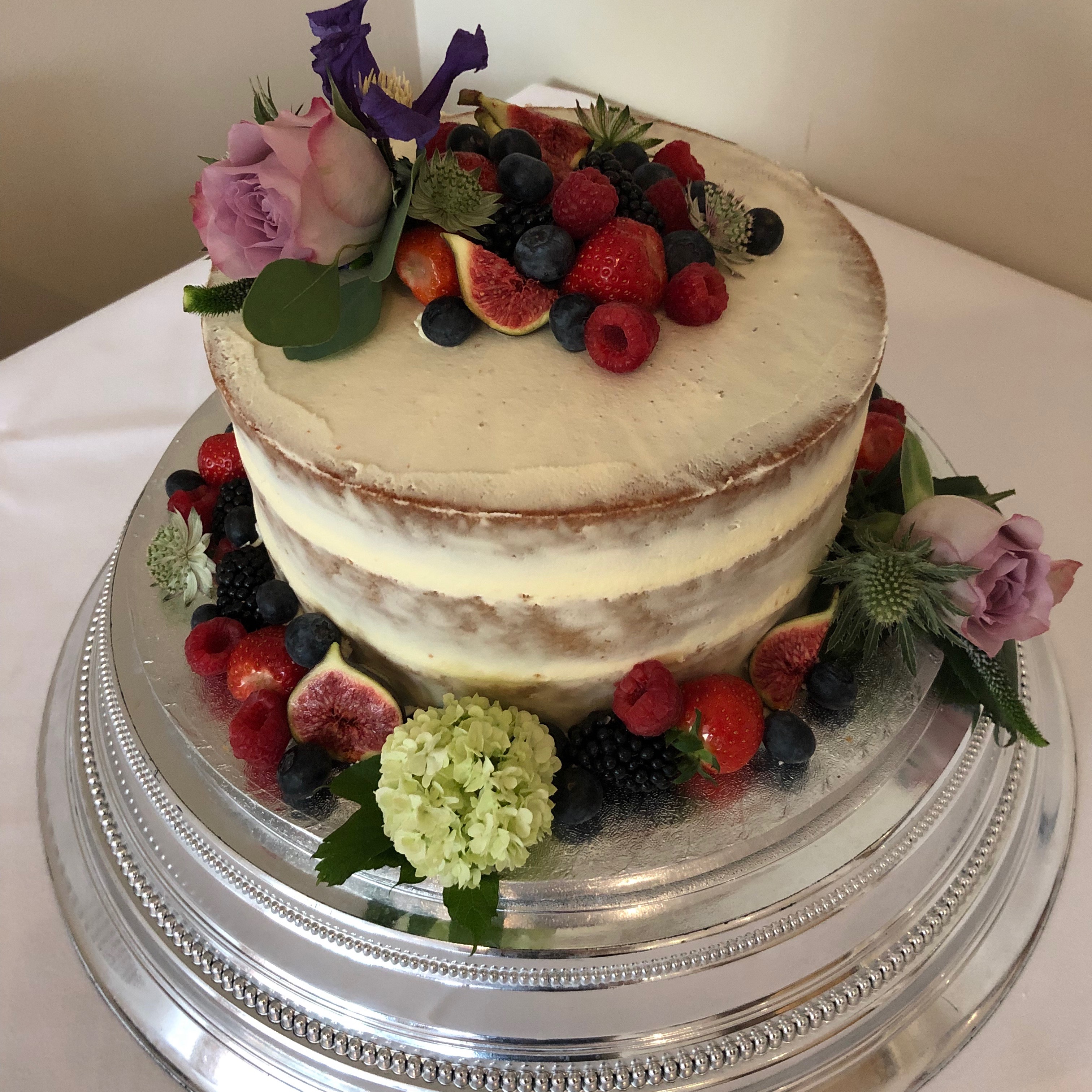 Semi-naked buttercream wedding cake with fresh fruit &amp; flowers